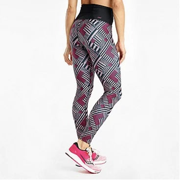 Person wearing patterned leggings and pink sneakers on a white background